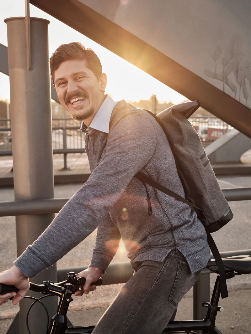 Ein lachender JobRadler fährt im Sonnenuntergang über eine Brücke Ein lachender JobRadler fährt im Sonnenuntergang über eine Brücke