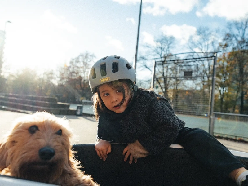 Maedchen klettert zum Hund ins Lastenrad, Hund ist unsicher wie er das findet