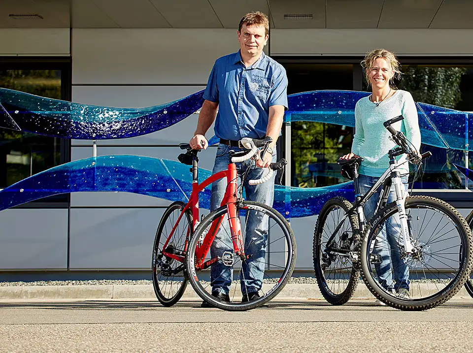 Zwei glückliche Menschen stehen mit ihrem JobRad vor dem Endress und Hauser Gebäude